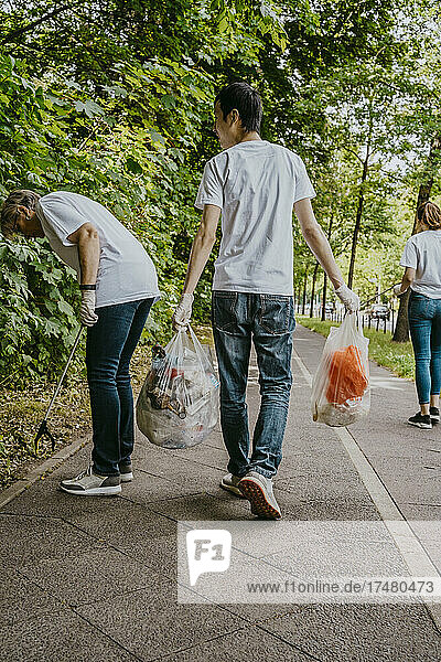 Male and female volunteers cleaning plastics on footpath