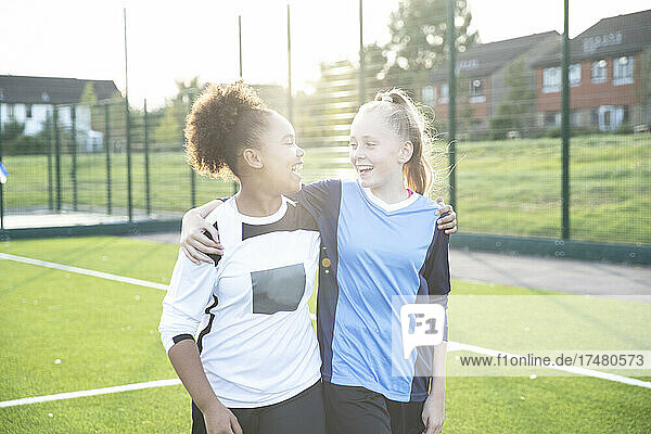 UK  Smiling female soccer team members (12-13) embracing in field