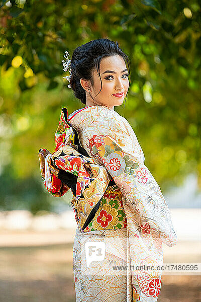 Portrait of smiling woman wearing kimono standing in park