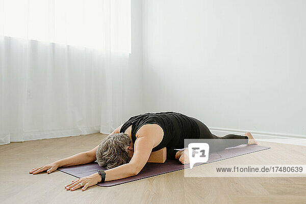 Woman in pigeon pose on yoga mat at home