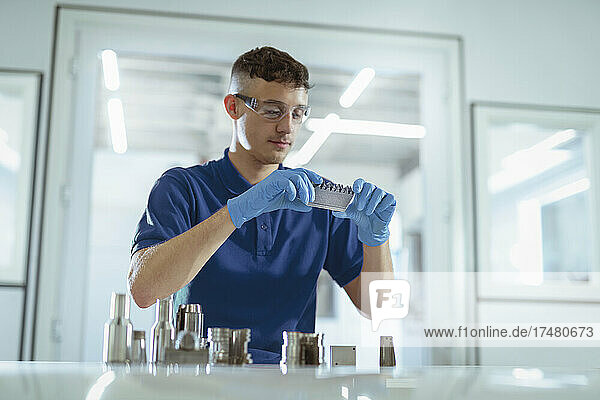 Man holding metal 3d printed objects in laboratory