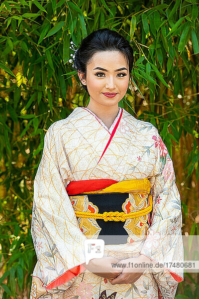 Portrait of smiling woman wearing kimono standing in park