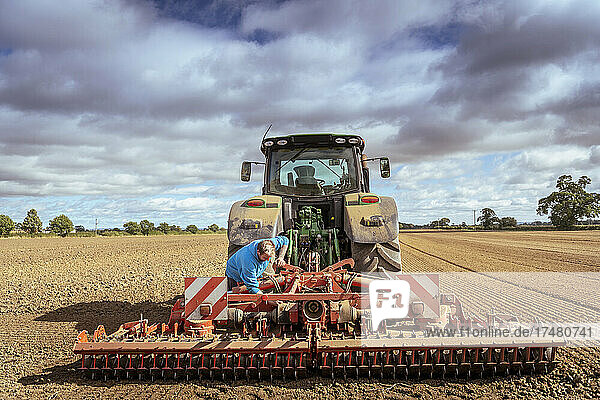 Farmer at tractor with cultivating plough in plowed field