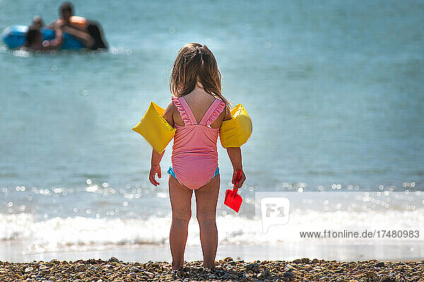 Rear view of girl wearing water wings on beach