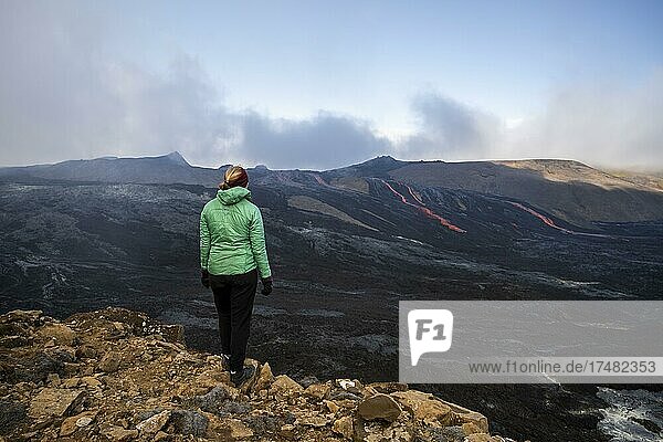 Tourist looking at erupting volcano with lava fountains and lava field  crater with erupting lava and lava flow  Fagradalsfjall  Krýsuvík volcano system  Reykjanes Peninsula  Iceland  Europe