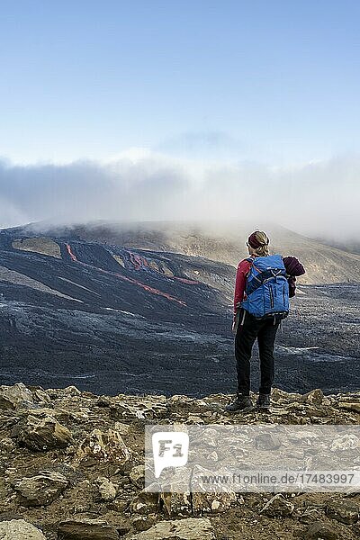 Touristin blickt auf ausbrechenden Vulkan mit Lavafontänen und Lavafeld  Krater mit heraustretender Lava und Lavafluss  Fagradalsfjall  Krýsuvík-Vulkansystem  Reykjanes Halbinsel  Island  Europa