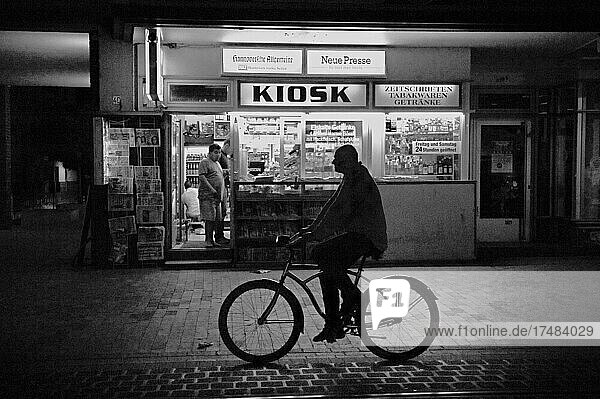 Mann auf Fahrrad vor Kiosk bei Nacht  nächtlicher Fahrradfahrer  Radfahrer auf Straße vor Kiosk  Hannover  Niedersachsen  Deutschland  Europa