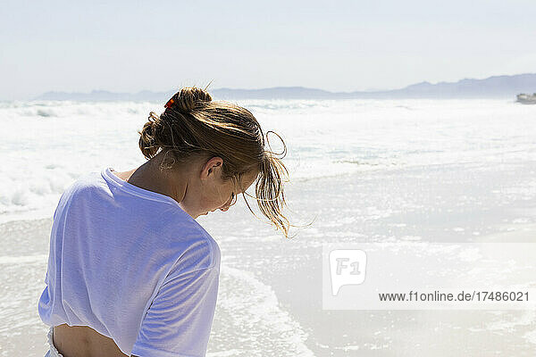 Teenage girl walking on a sandy beach at the water's edge