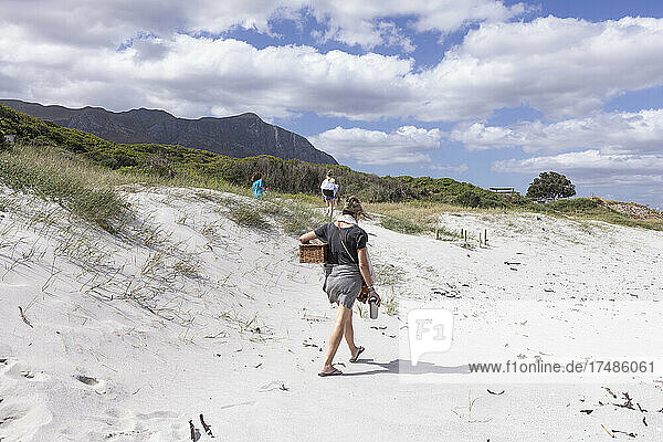 Adult woman carrying picnic basket on Grotto Beach  Hermanus  Western Cape  South Africa.