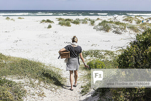 Erwachsene Frau mit Picknickkorb am Grotto Beach  Hermanus  Westkap  Südafrika.