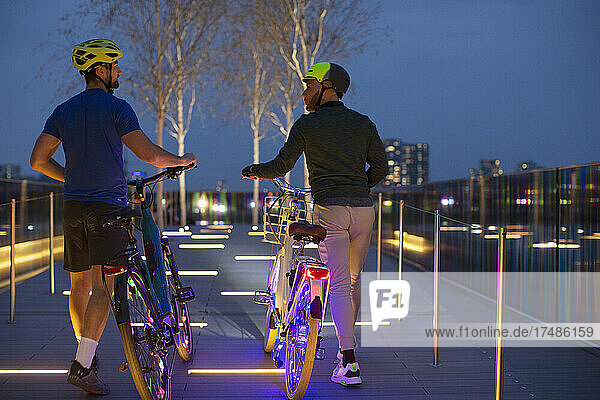 Männer mit beleuchteten Fahrrädern auf einem städtischen Fußweg  London  UK
