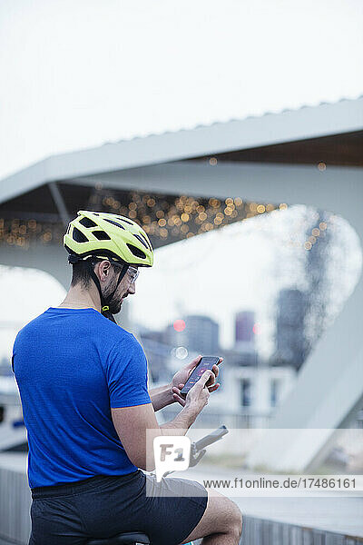 Mann auf Fahrrad mit Smartphone in der Stadt