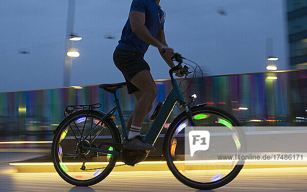 Mann fährt beleuchtetes Fahrrad bei Nacht