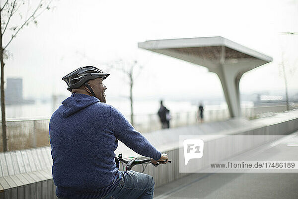 Mann fährt Fahrrad auf städtischer Promenade