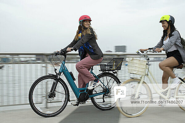 Junge befreundete Frauen fahren Fahrrad auf einer städtischen Brücke