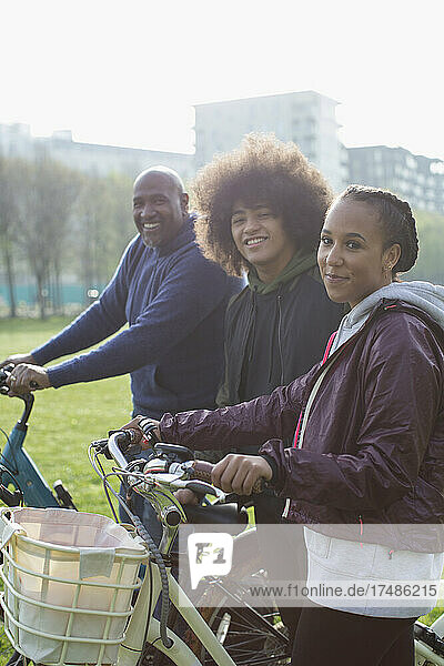 Portrait glückliche Familie auf Fahrrädern im sonnigen Park