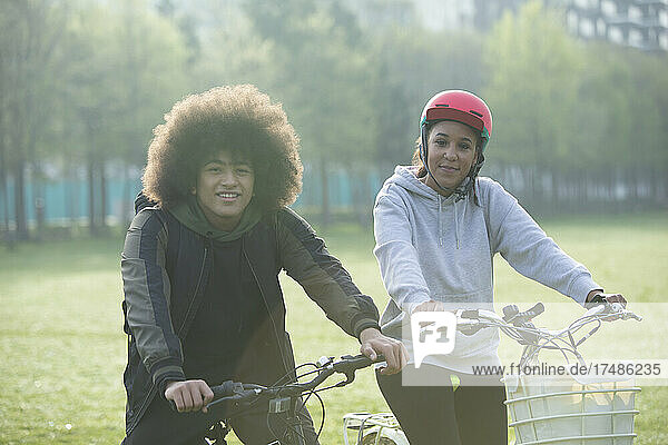 Porträt Teenager-Zwillinge auf Fahrrädern im Park