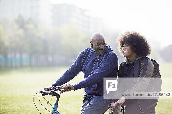 Happy father and son on bicycles in sunny urban park