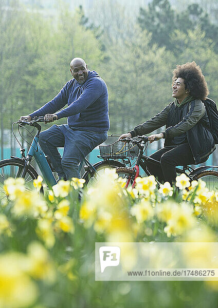 Glücklicher Vater und Teenager-Sohn beim Fahrradfahren im Frühlingspark