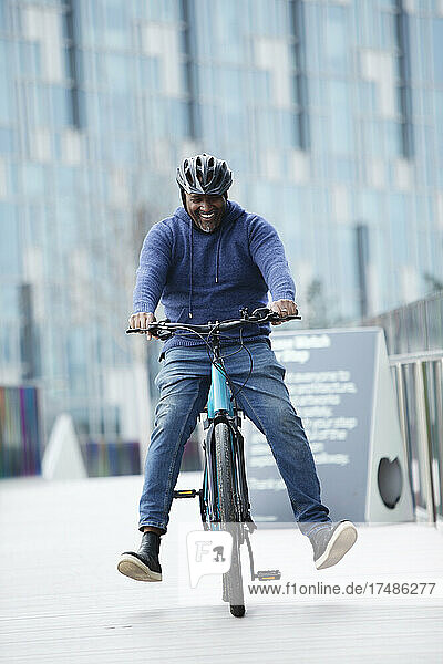 Glücklicher Mann fährt Fahrrad auf dem Bürgersteig