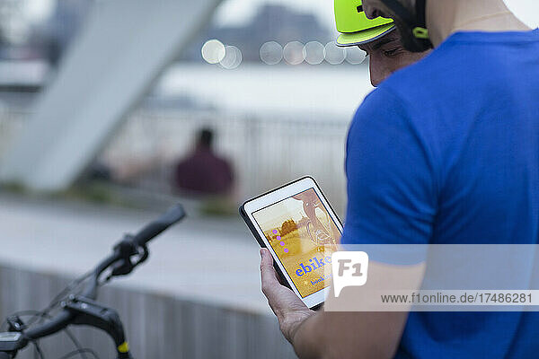 Männer mit digitalem Tablet  die mit einer mobilen App ein Fahrrad mieten