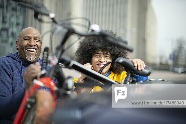Porträt glücklicher Vater und Sohn mit. Fahrrädern auf städtischem Bürgersteig