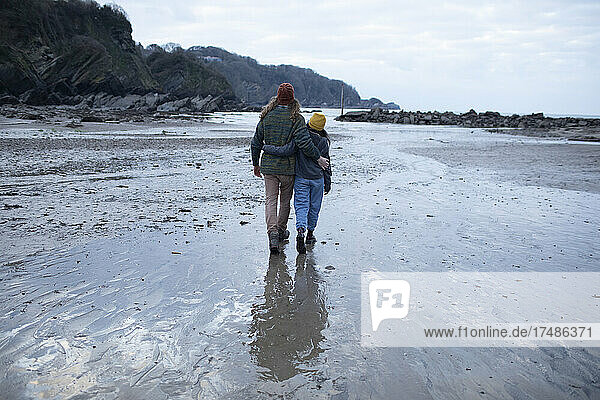 Zärtliches junges Paar  das am nassen Sandstrand spazieren geht