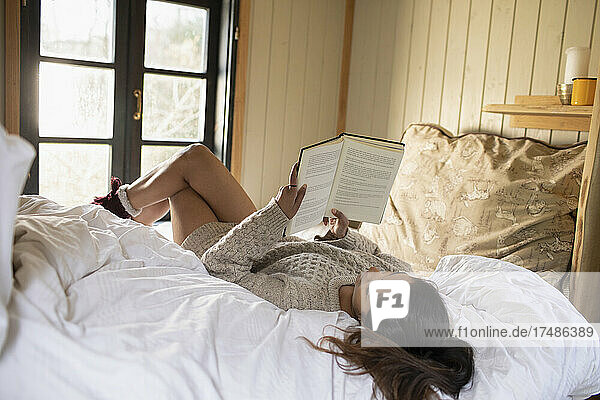 Junge Frau liest ein Buch in einer kleinen gemieteten Hütte