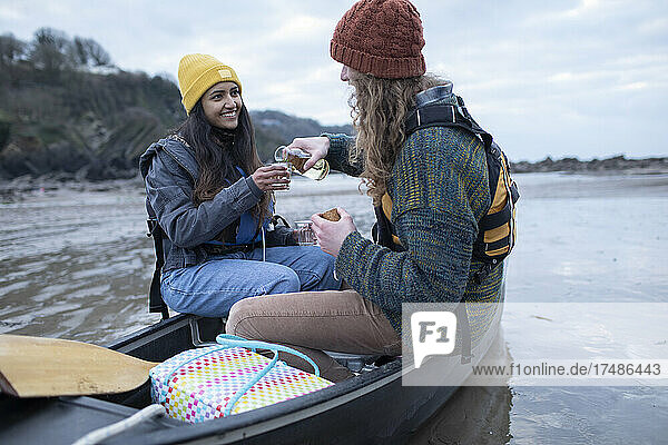 Glückliches junges Paar trinkt Wein in einem Kanu am Strand