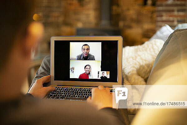Man video conferencing with colleagues at laptop screen