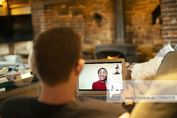 Mann hält Videokonferenz mit Kollegen am Laptop im Wohnzimmer
