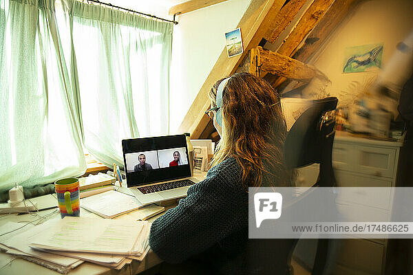 Frau hält Videokonferenz mit Kollegen auf dem Laptop-Bildschirm zu Hause