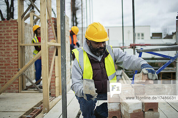 Männlicher Bauarbeiter beim Verlegen von Ziegeln auf einer Baustelle