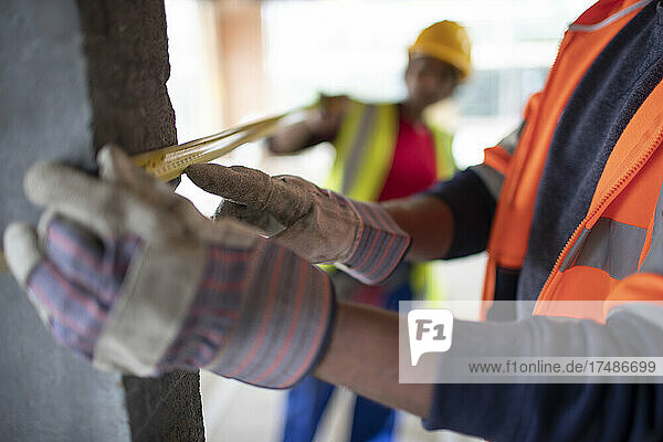 Close up construction workers using tape measure