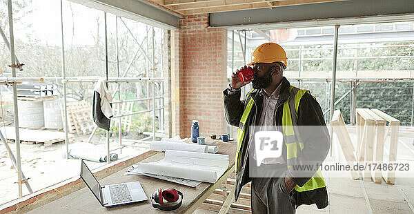 Männlicher Architekt trinkt Kaffee auf einer Baustelle