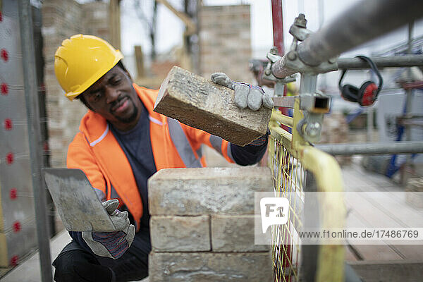 Male construction worker laying bricks at construction site