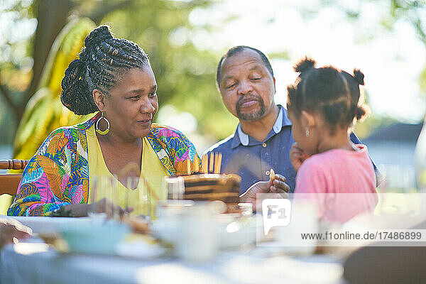 Grandparents and granddaughter enjoying birthday cake on patio