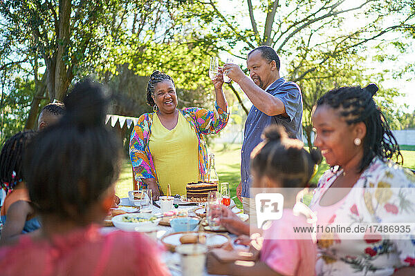 Glückliche Mehrgenerationen-Familie feiert Geburtstag im sommerlichen Hinterhof