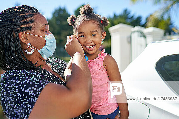 Porträt Mutter hilft süßes Kleinkind Tochter mit Gesichtsmaske