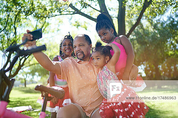 Großvater und Enkeltöchter machen ein Selfie im Sommerpark