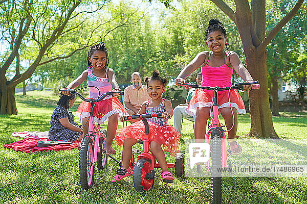 Portrait carefree sisters riding bikes in sunny summer park