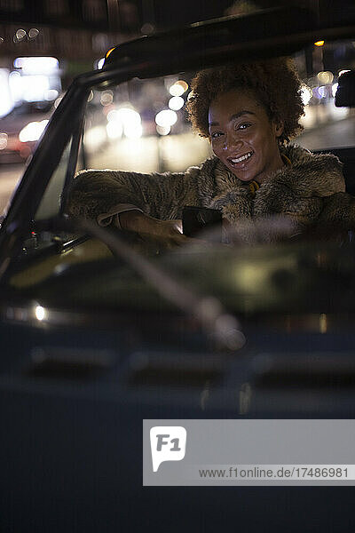 Porträt glückliche junge Frau fährt Cabrio bei Nacht