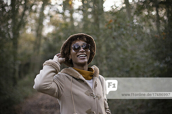 Carefree young woman in hat and sunglasses in autumn park