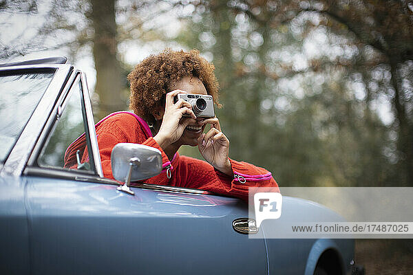 Junge Frau mit Digitalkamera im Cabrio