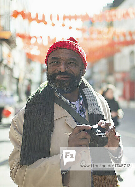 Portrait handsome male tourist with digital camera in sunny city