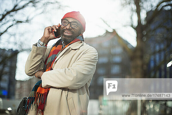 Happy businessman talking on smart phone in city