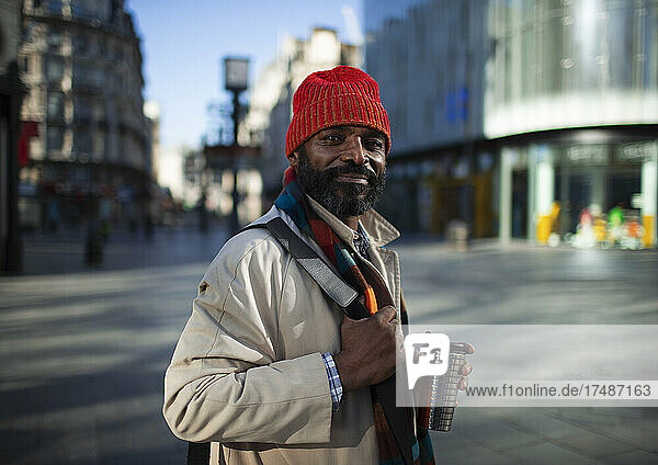 Porträt selbstbewusster gutaussehender Geschäftsmann mit Strumpfmütze auf einer Stadtstraße