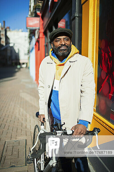 Porträt selbstbewusster gut aussehender Mann mit Fahrrad auf sonnigem Gehweg