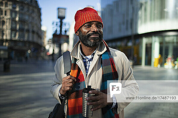 Portrait handsome businessman in stocking cap with coffee in city
