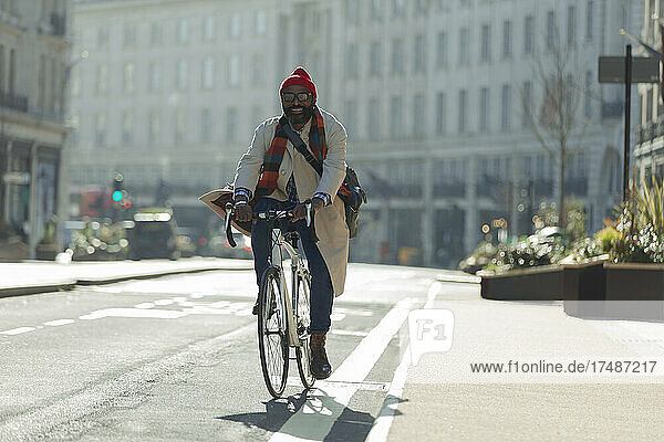 Männlicher Pendler auf dem Fahrrad auf einer sonnigen Straße in der Stadt